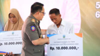 Pj Gubernur Jawa Timur, Adhy Karyono, memberikan santunan secara simbolis kepada ahli waris petugas Pemilu 2024 yang meninggal. (Foto: Ambang)