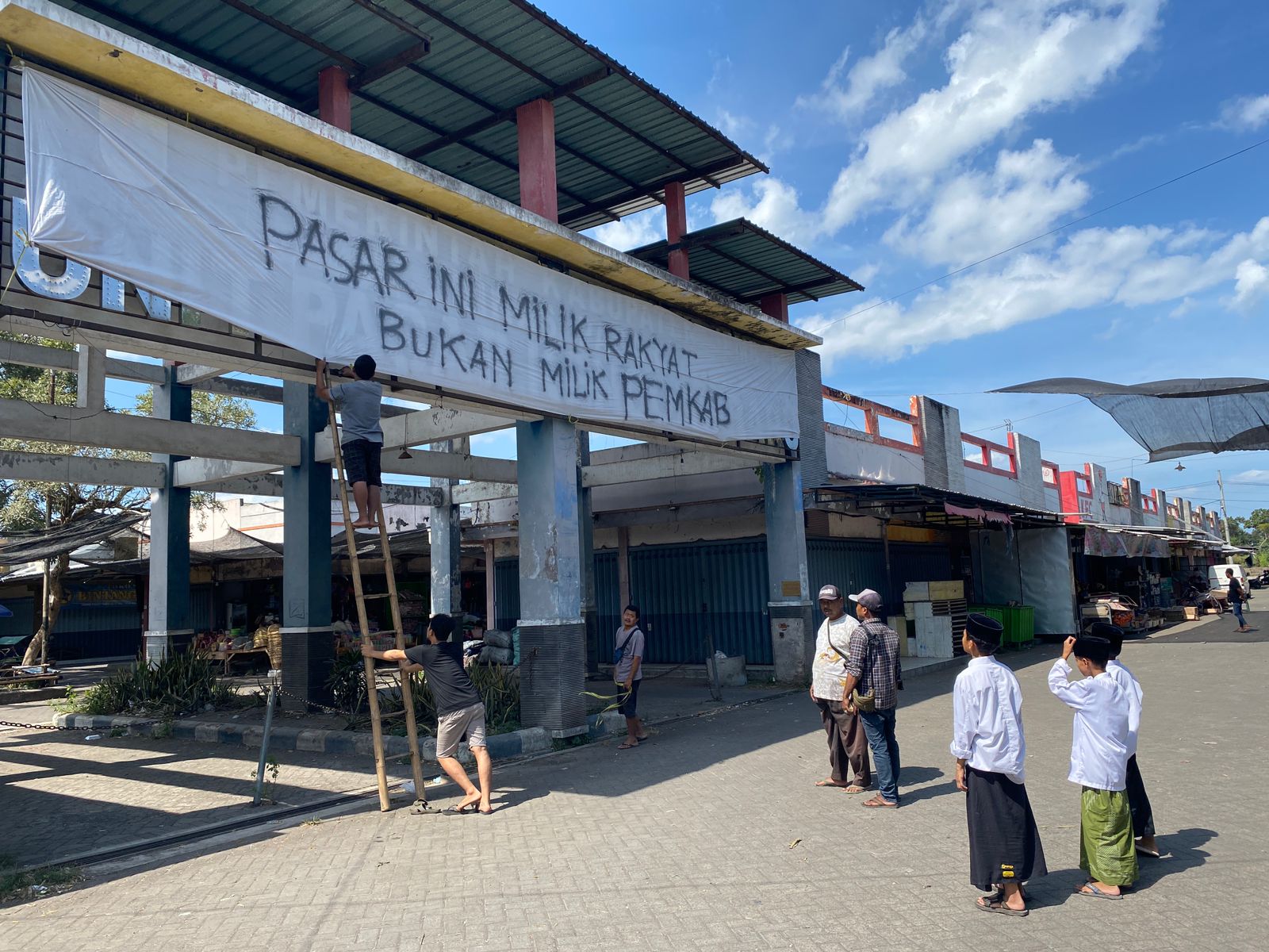 Pedagang Pasar Baru Kencong menutup logo Pemkab Jember menggunakan kain warna putih. (Foto: Istimewa)