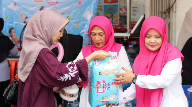 Petugas Alfamart saat memberikan popok Baby Happy di depan gerai (Foto: Istimewa).